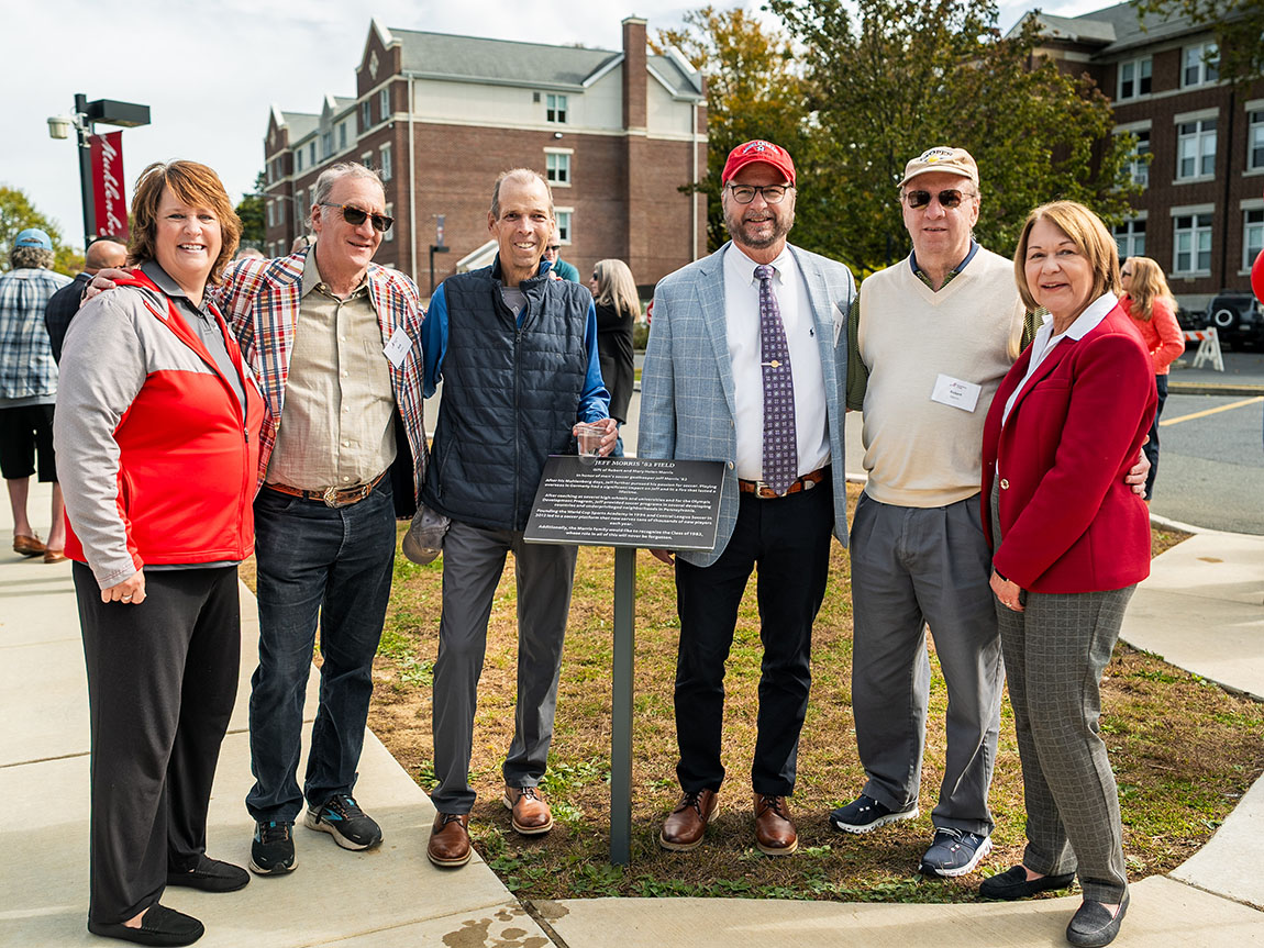 A group of six people poses for a photo around a plaque